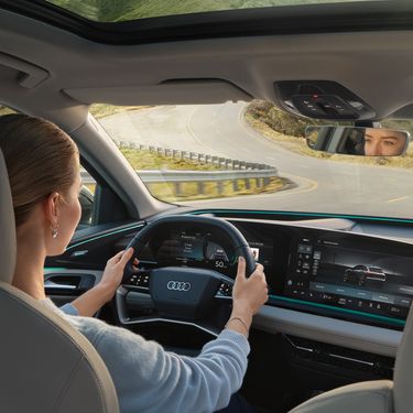 Woman sits in Audi and uses the Audi assistant via MMI-display